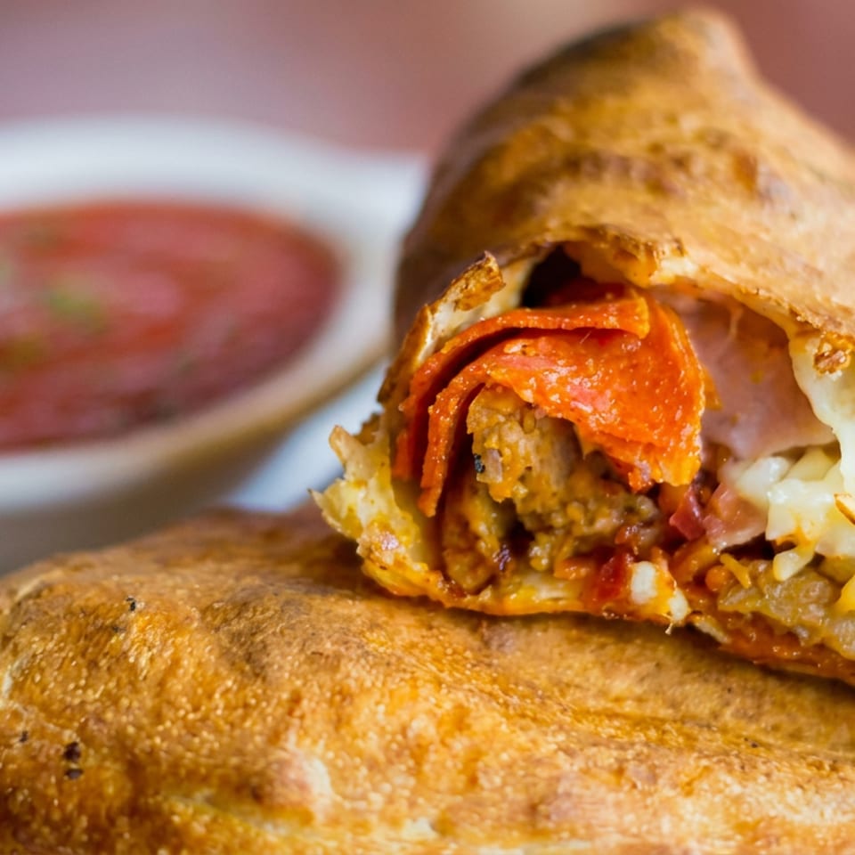 Sliced toasted sandwich filled with meatballs, pepperoni, tomato sauce, and melted cheese, served with marinara dipping sauce.